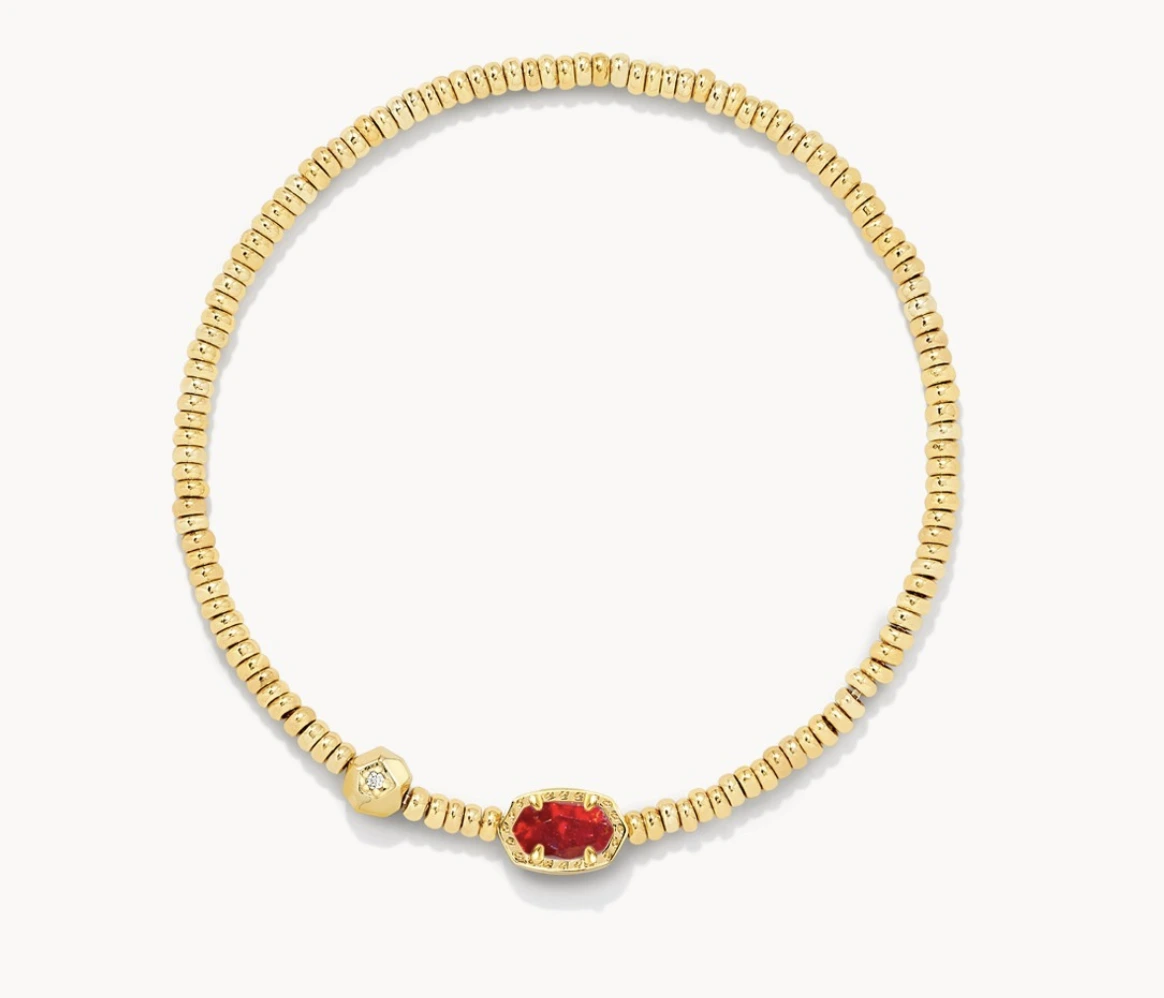 Gold-tone beaded stretch bracelet with a red center stone in an oval gold frame, shown on a white background.