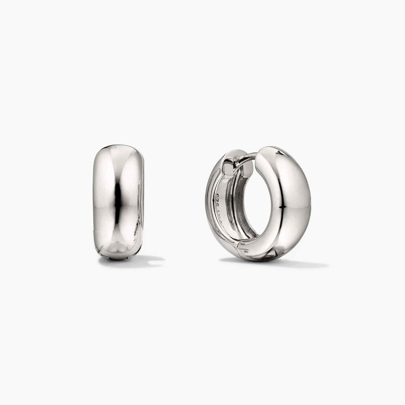 A pair of chunky silver hoops earrings on a neutral background. The hoops feature a post and clicker closure.