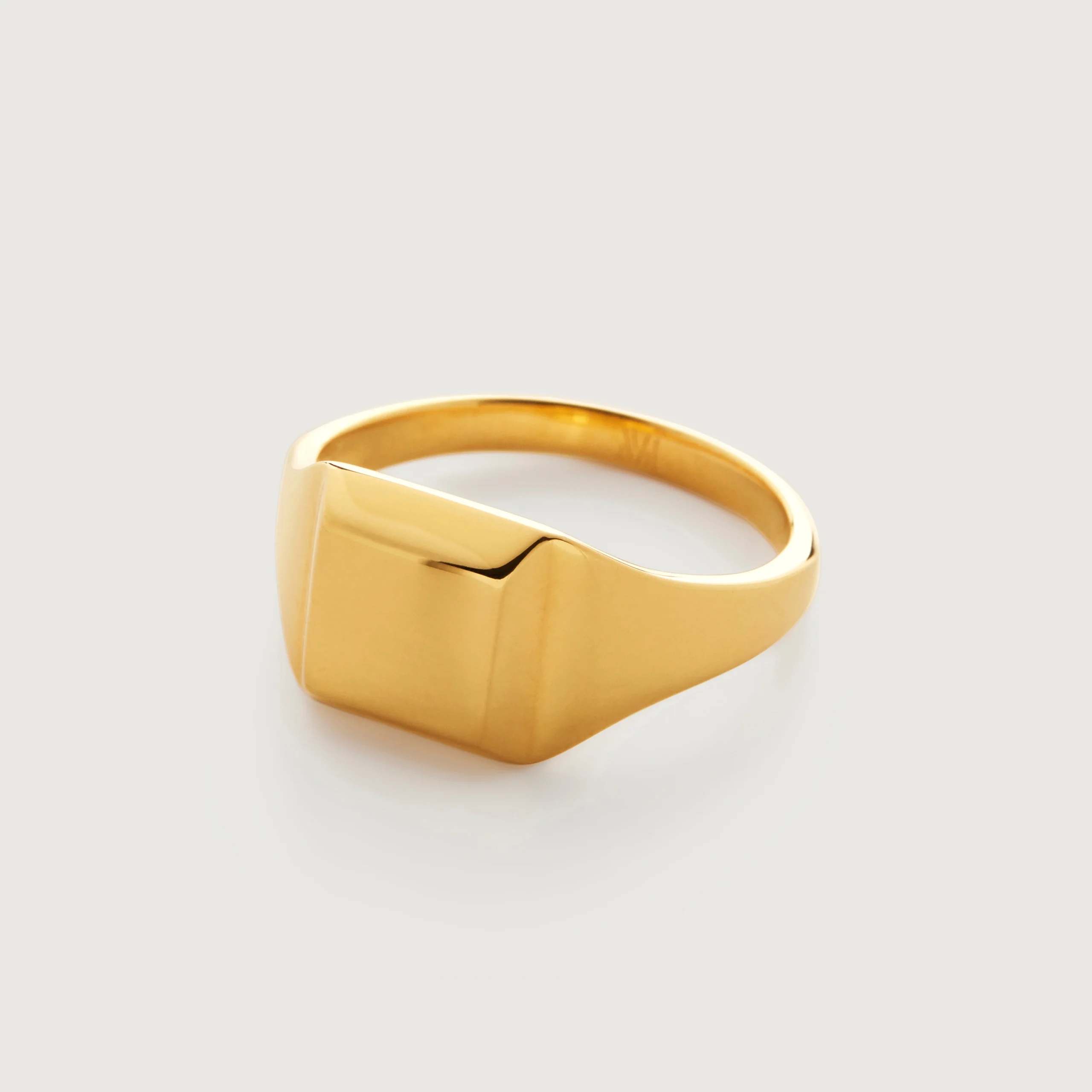 Gold signet ring with a smooth, square face, shown on a plain light gray background.